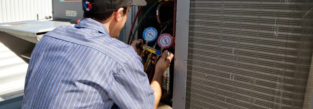 HVAC technician servicing a condenser unit in Paola
