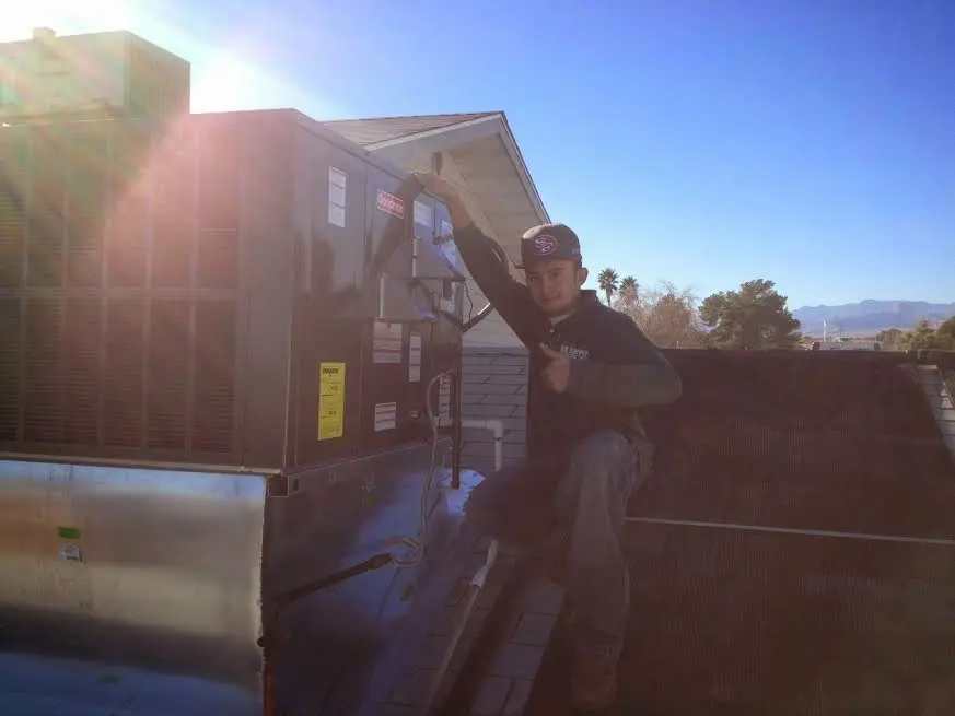 HVAC technician performing AC Tune-Up on a rooftop unit in Paola